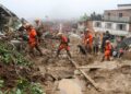 a group of people in orange uniforms walking up a muddy hill